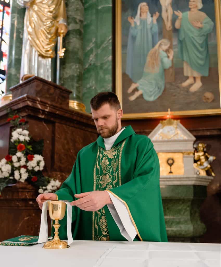 A Catholic priest in mass preparing a golden goblet of wine.