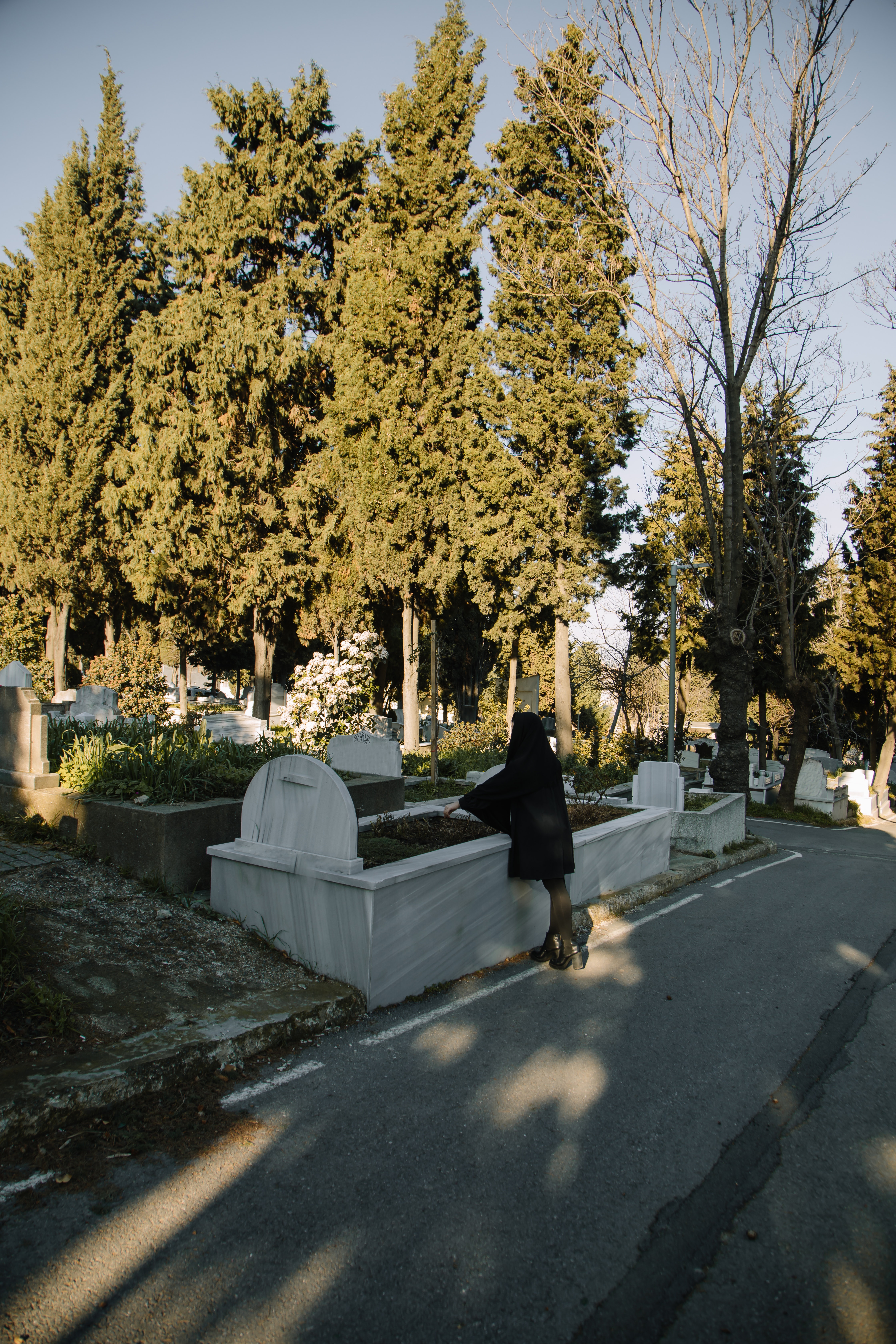 A woman stands at a grave in mourning for the dead.