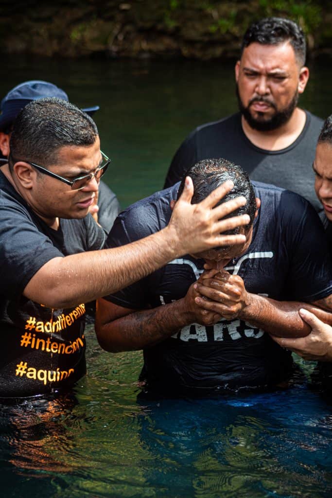 A pastor baptizes a man in a river.