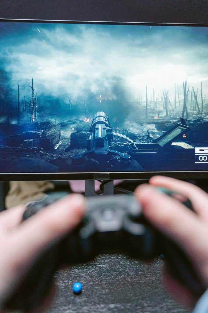 Image from Pexels by Tima Miroshnichenko. A person playing a violent and graphic first-person shooter online game.