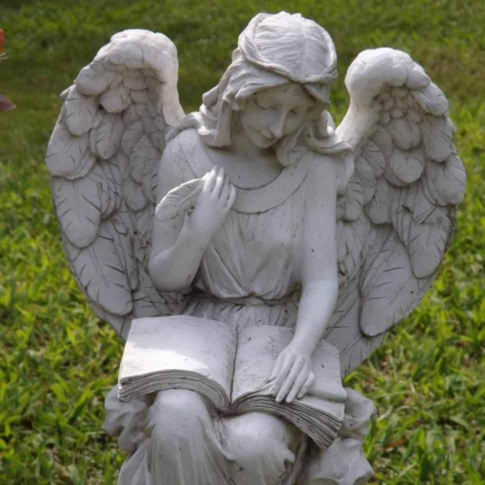 Statue of an angel writing in a book